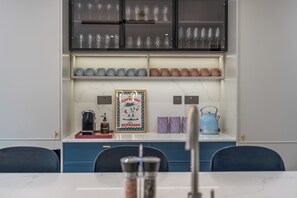 Eine Küche mit Marmorarbeitsplatte, einer Kaffeemaschine, einem Wasserkocher und einem gerahmten Bild.