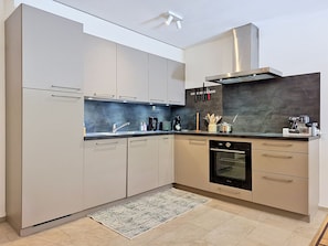 A modern kitchen with a built-in oven, a coffee maker, and a range hood. - Les Ambassadeurs B 3 by Interhome (Crans-Montana)