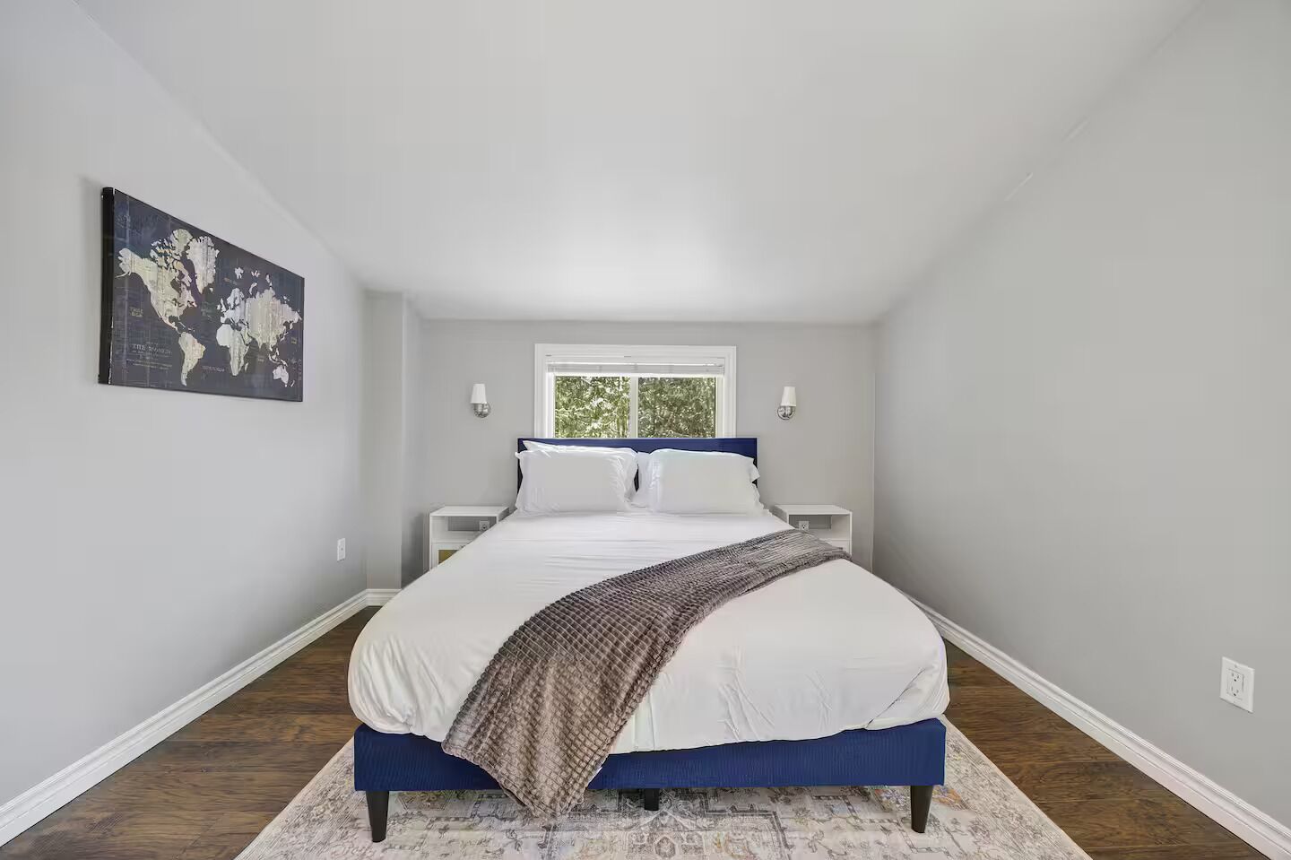 Une chambre à coucher avec un lit, une carte du monde accrochée au mur et une fenêtre.