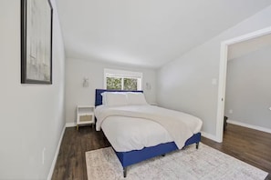 Une chambre à coucher avec un lit, une table de chevet, une fenêtre et une porte.