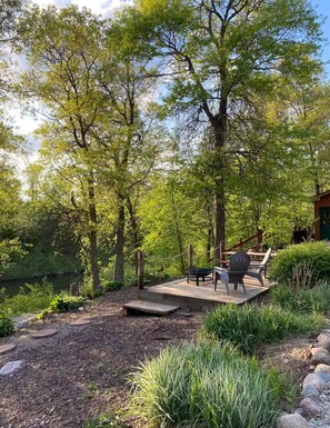 An outdoor seating area with a table and chairs, surrounded by trees and a wooden deck.