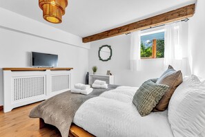 Ein modernes Schlafzimmer mit Bett, Fernseher, Kamin und Fenster mit Blick.