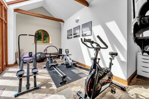 A home gym with exercise equipment, a yoga mat, and a window with a view of greenery. - Luxury Stay Sleeps 14 Near M 6 (Newcastle Under Lyme)