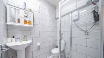 A modern bathroom with a white sink, toilet, and glass-enclosed shower.