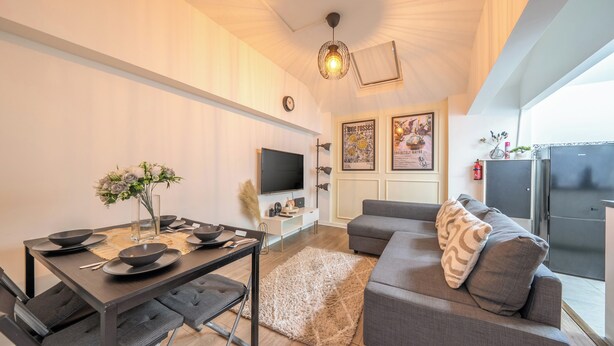 Uma sala de estar moderna com área de jantar, televisão de tela plana e sofá com almofadas decorativas.