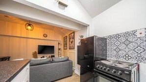 Uma cozinha moderna com forno embutido, uma geladeira preta e um espaço de refeições com sofá.