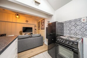 A modern kitchen with a built-in oven, a black refrigerator, and a dining area with a sofa. - Luxury Apartment6 - City Centre Manchester (Manchester)