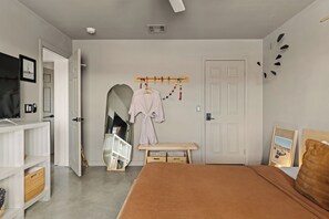 A bedroom with a bed, a TV, a wardrobe, a mirror, and a door. - Dark Star - Endless Stars, Cowboy Pool, Spa, Fire pit, BBQ (Twentynine Palms)