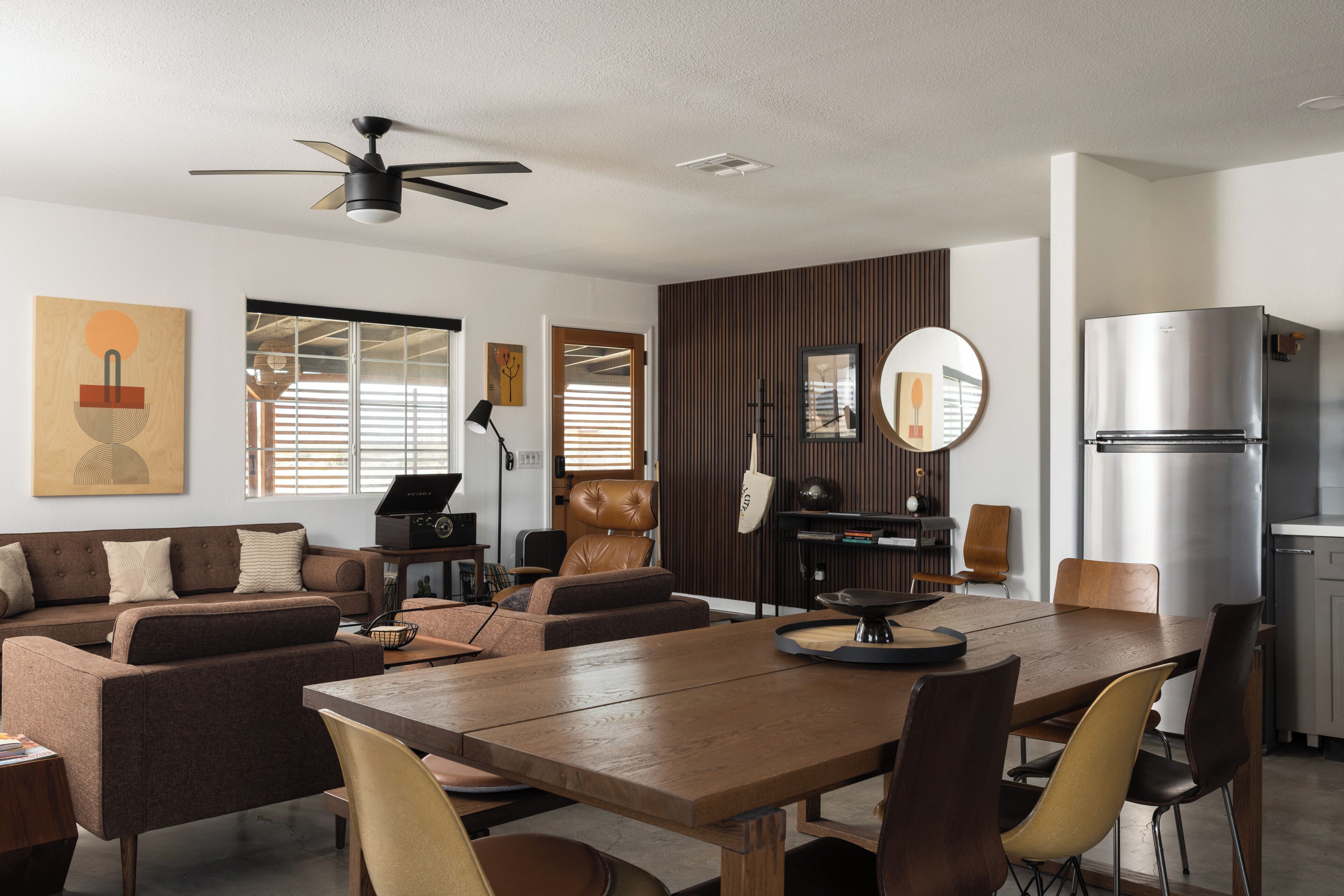 Un espacio moderno para vivir con zona de comedor, conjunto de sofás y cocina con refrigerador incorporado.