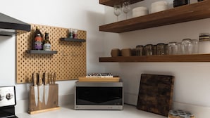 A kitchen with a pegboard holding bottles, a microwave, and a knife block.