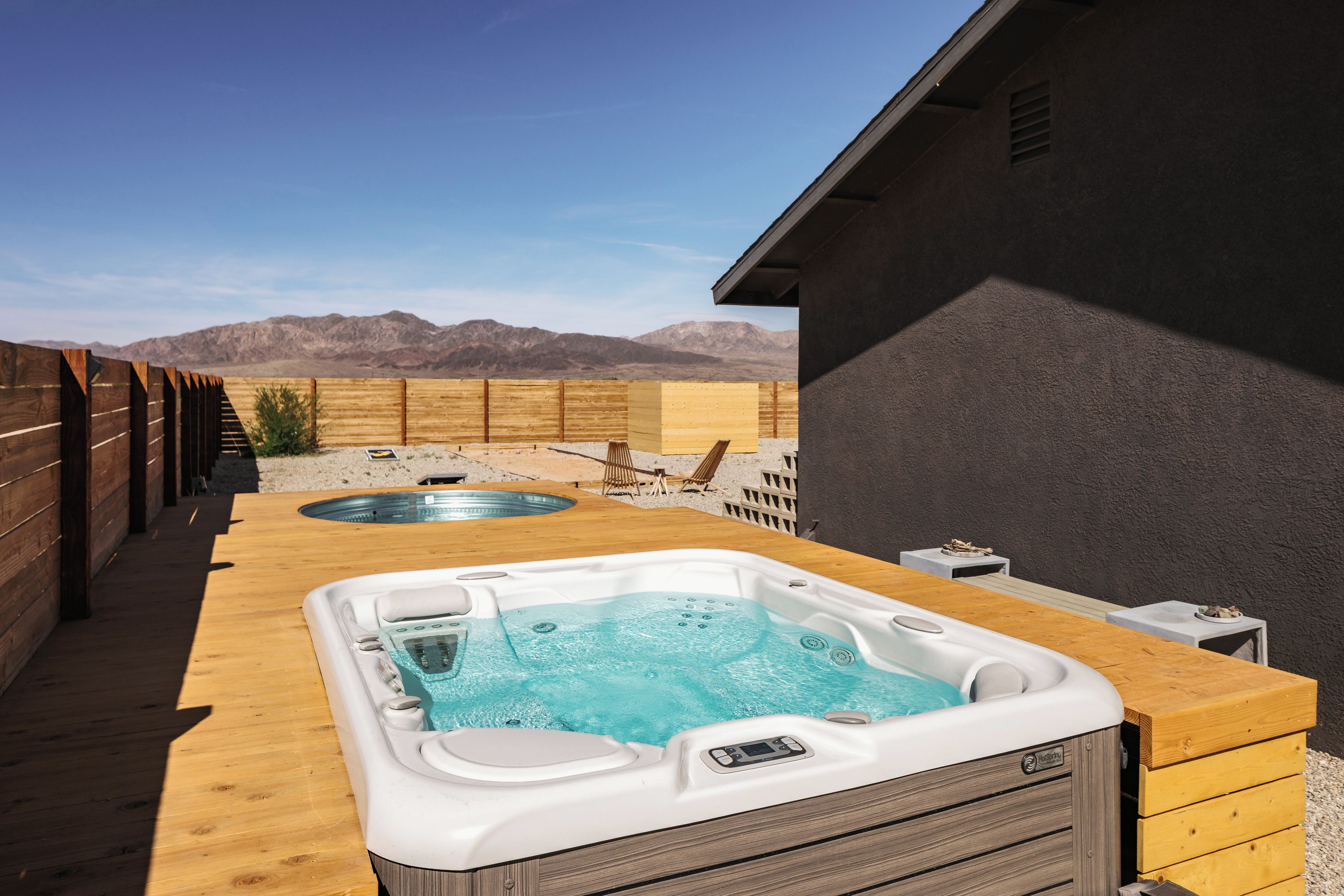 Un espace avec deux bains à remous, une terrasse en bois et une vue sur la montagne.