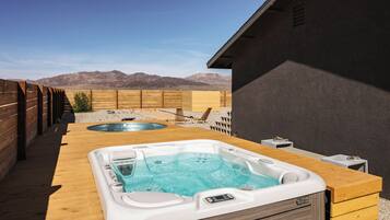 Un espace avec deux bains à remous, une terrasse en bois et une vue sur la montagne.