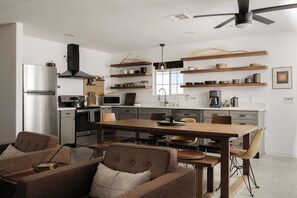 Uma cozinha moderna com ilha central, eletrodomésticos embutidos e prateleiras de madeira.