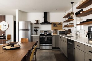 A modern kitchen with stainless steel appliances, wooden cabinets, and a central island. - Dark Star - Endless Stars, Cowboy Pool, Spa, Fire pit, BBQ (Twentynine Palms)