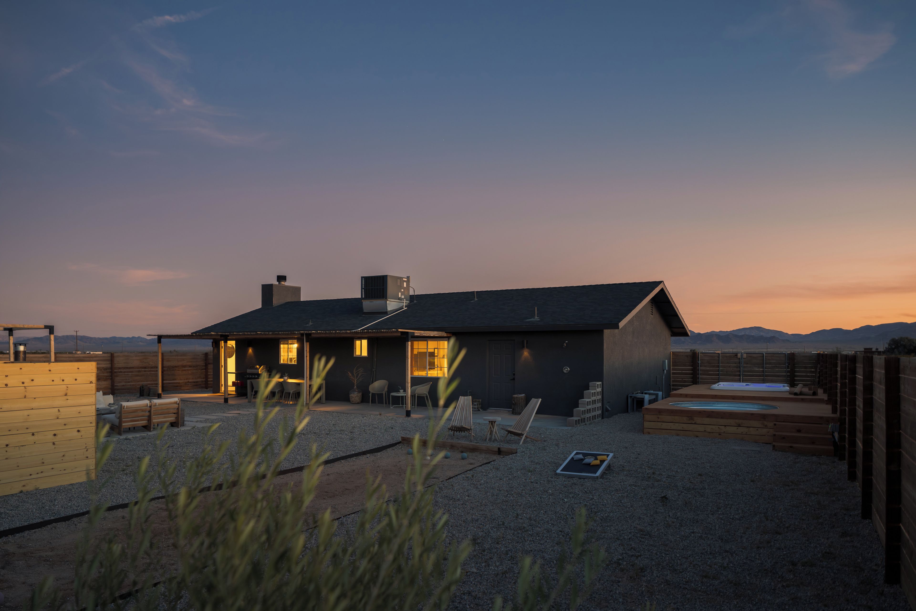A modern house with a patio area, outdoor seating, and a swimming pool.