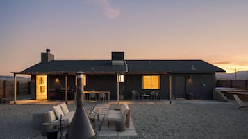 Una casa moderna con un patio, mobiliario exterior y vistas a las montañas.