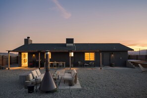 Une maison moderne dotée d’un patio, d’un espace salon extérieur et offrant une vue sur les montagnes.