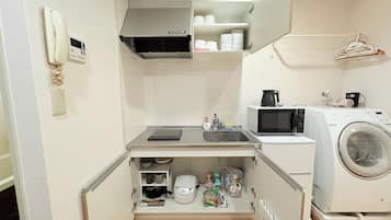 A compact kitchenette with a microwave, coffee maker, and washing machine.