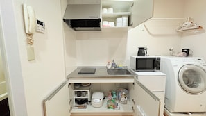 A compact kitchenette with a microwave, coffee maker, and washing machine.