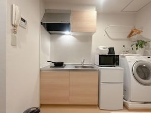 Une cuisine compacte équipée d’un four à micro-ondes, d’un évier et d’un petit réfrigérateur.