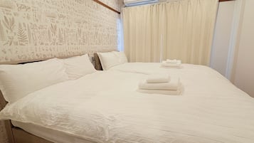 Ein Hotelzimmer mit einem großen Bett, einem Blattmuster-Kopfende und einem mit Vorhängen versehenen Fenster.