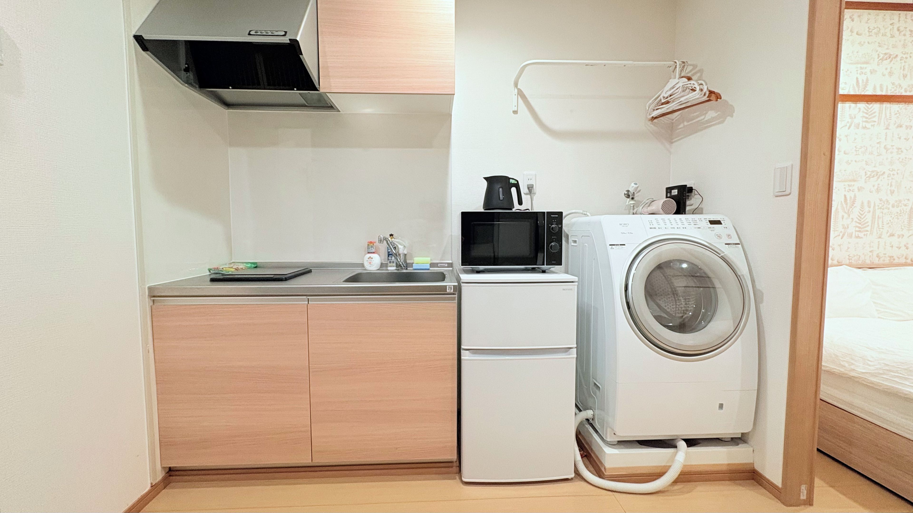 Une petite cuisine équipée d’un four à micro-ondes, d’un petit réfrigérateur et d’un lave-linge.