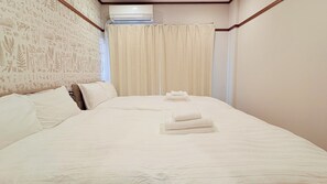 Habitación de hotel con una cama grande, un cabecero de madera, aire acondicionado de pared y una cortina.