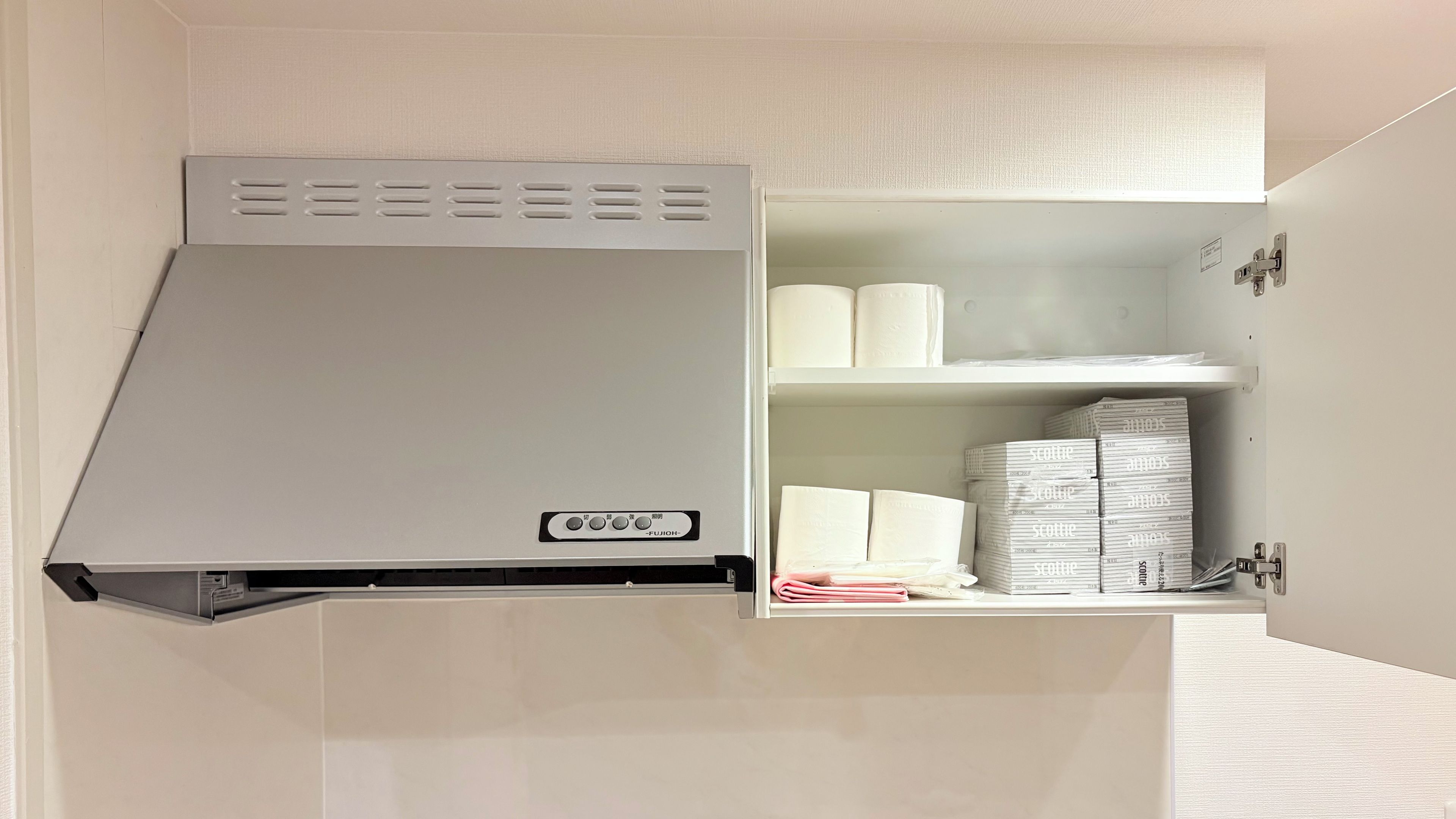 Un meuble blanc équipé d’un radiateur intégré et d’une étagère où sont rangées des serviettes pliées et des articles emballés.