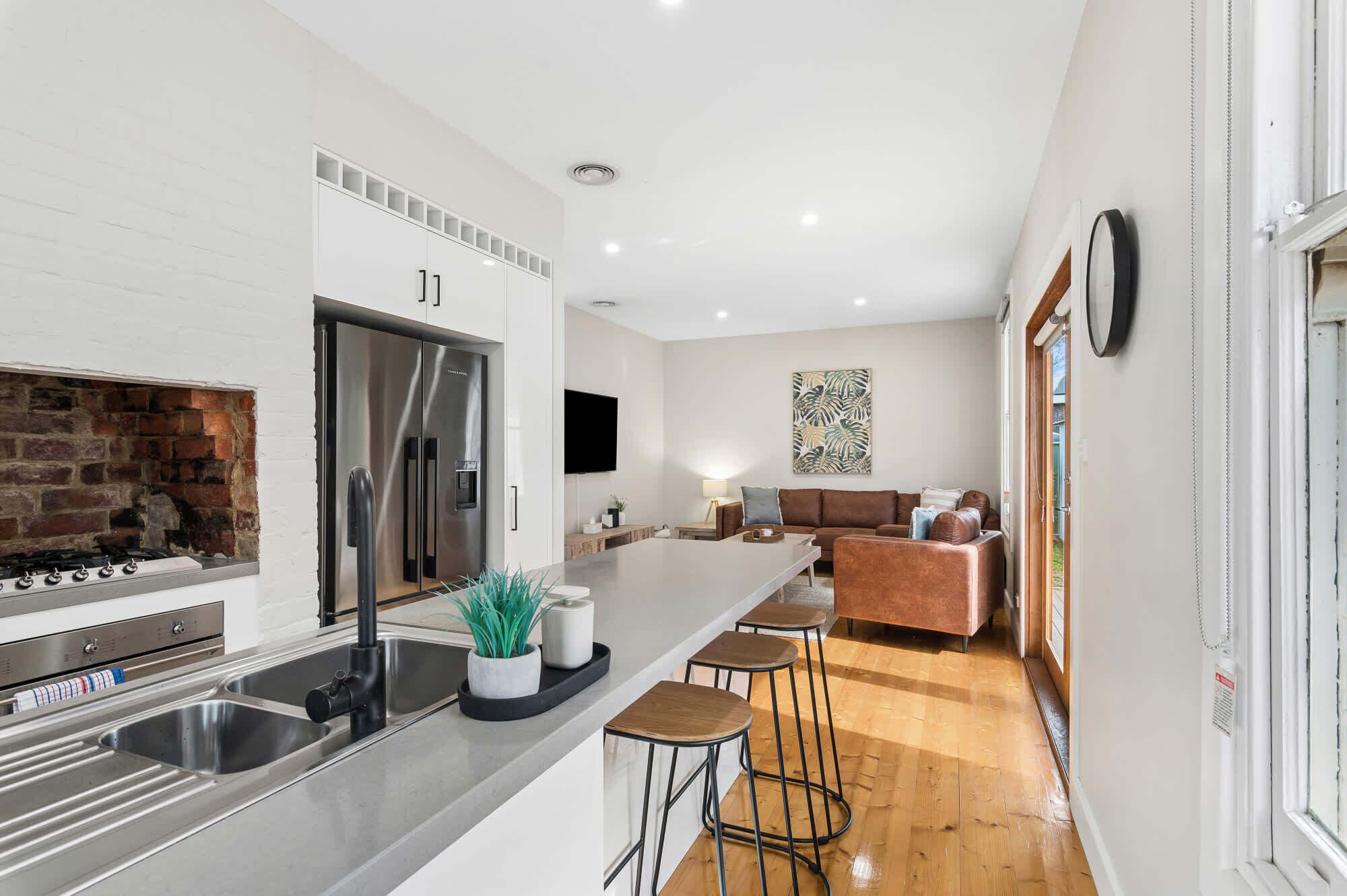 A modern kitchen with a stainless steel refrigerator, double sink, and a brick oven.
