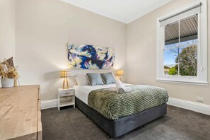 A bedroom with a bed, two bedside tables, a window, and a painting on the wall. - Central Bendigo Charmer, Sleeps 6 (Bendigo)