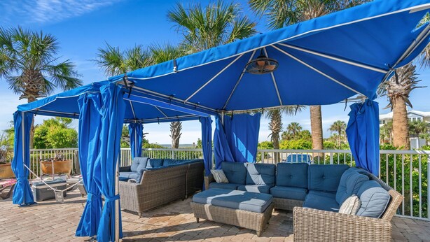 An outdoor seating area with wicker furniture and a blue canopy. - Oceanfront Penthouse, Pool, Lazy River & Waterpark (North Myrtle Beach)