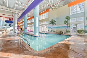 Ein Hallenbad mit freiem Blick auf Decke und Wände, inklusive Sicherheitsschildern und einem Wandgemälde mit Strandmotiv.
