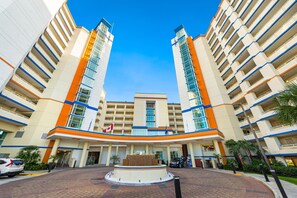 A hotel with a central courtyard, multiple floors, and a flag. - Oceanfront Penthouse, Pool, Lazy River & Waterpark (North Myrtle Beach)