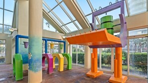 A spacious indoor area with large windows, colorful structural columns, and a central orange beam. - Oceanfront Penthouse, Pool, Lazy River & Waterpark (North Myrtle Beach)
