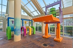 A spacious indoor area with large windows, colorful structural columns, and a central orange beam. - Oceanfront Penthouse, Pool, Lazy River & Waterpark (North Myrtle Beach)
