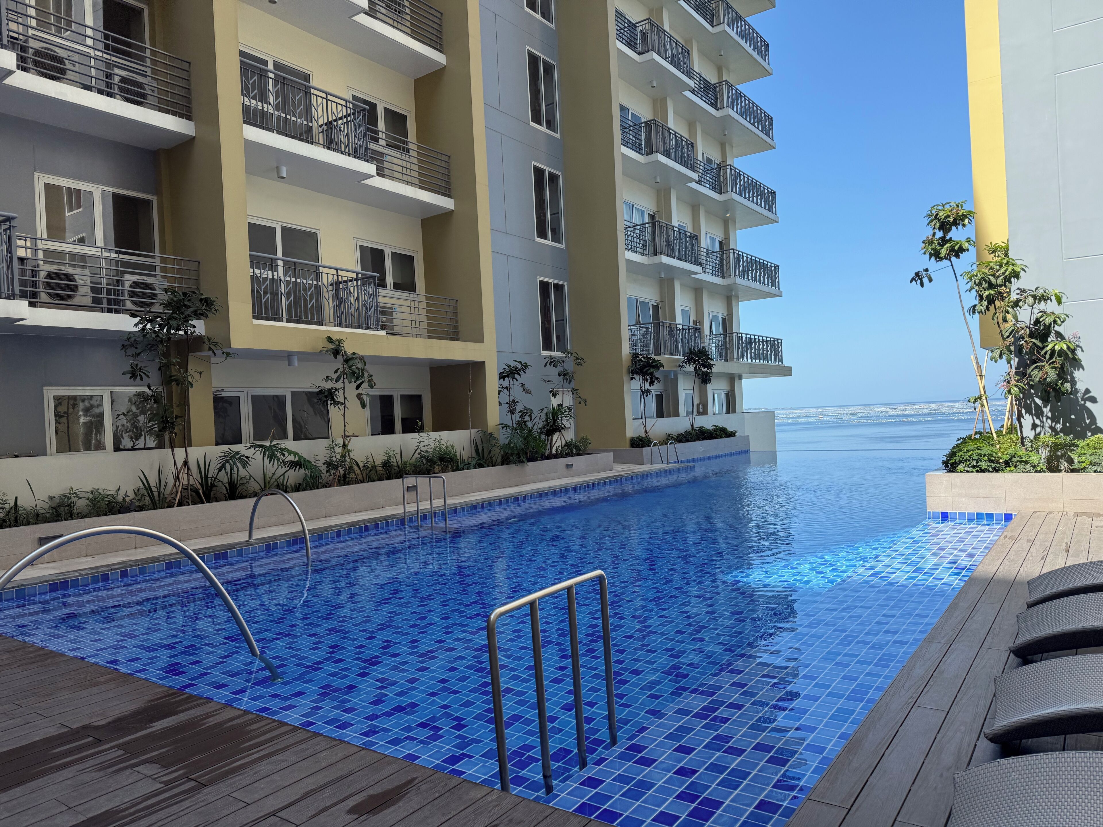 Un hotel moderno con piscina, balconi e vista sul mare.