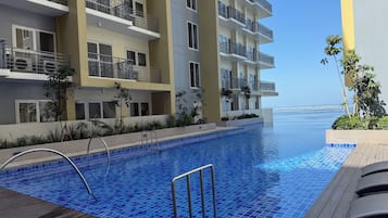 Un hotel moderno con piscina, balconi e vista sul mare.