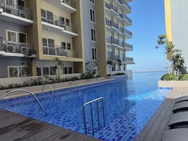 Un hotel moderno con piscina, balcones y vistas al mar.