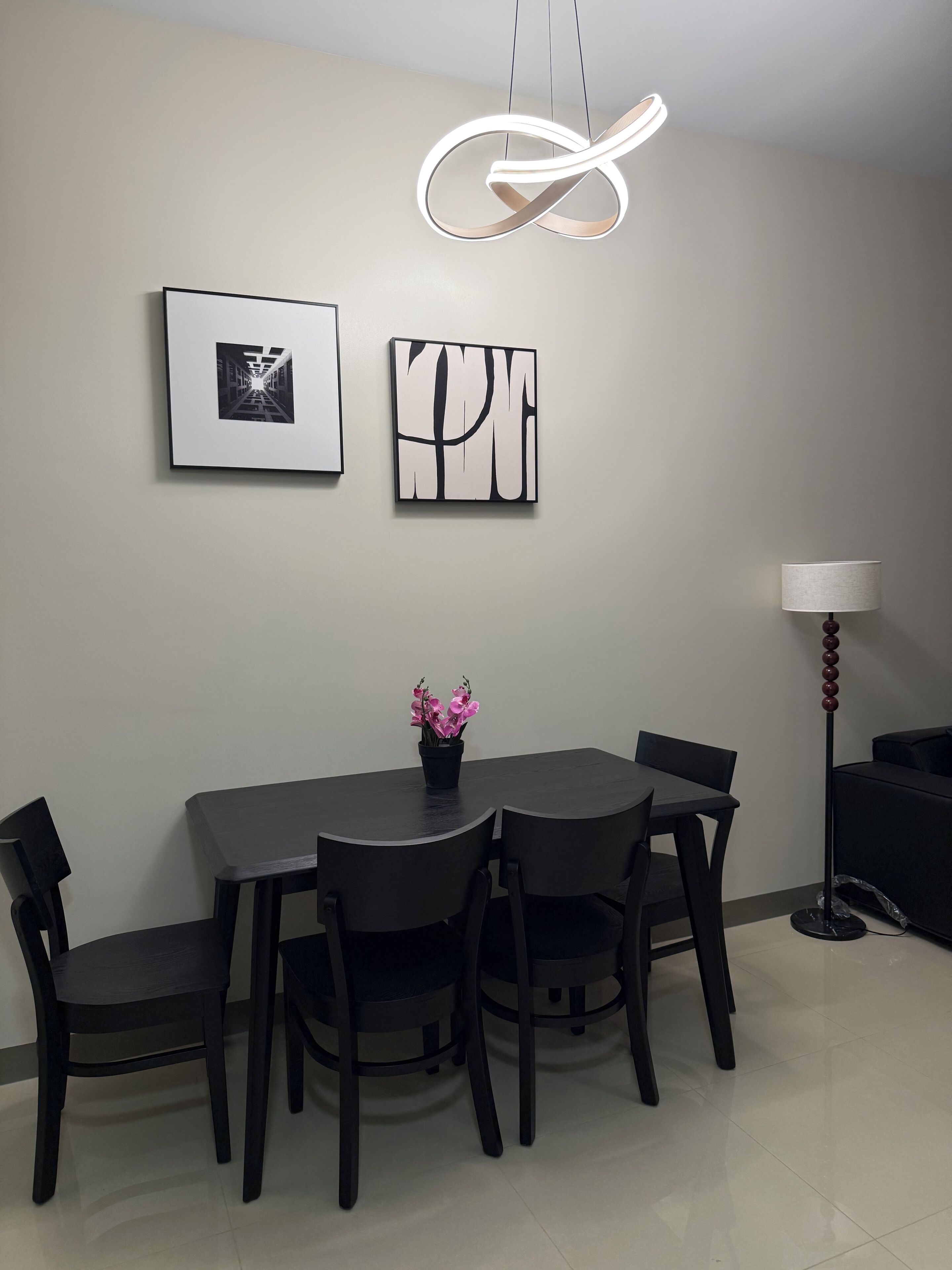 A dining area with a round table, four chairs, a potted plant, and wall art.