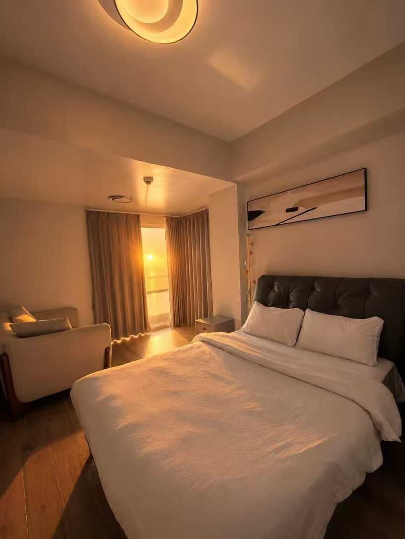 A hotel room with a large bed, a seating area, and a view of the outdoors.