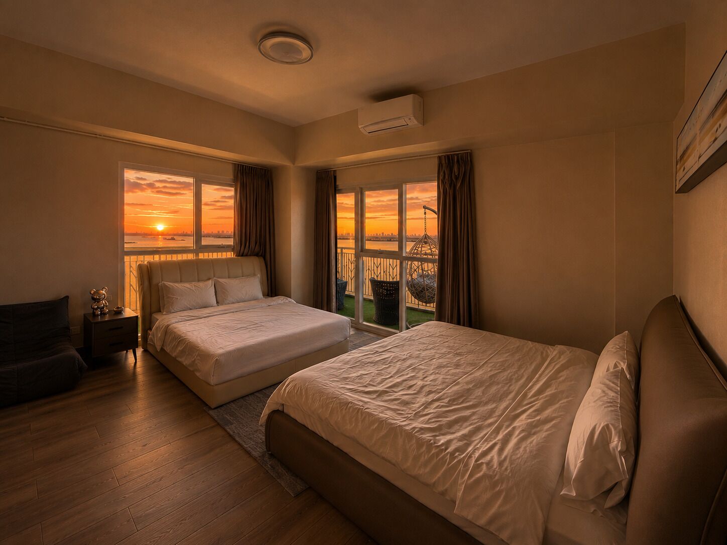 A hotel room with two beds, a nightstand, a chair, and a view of a sunset over a body of water.