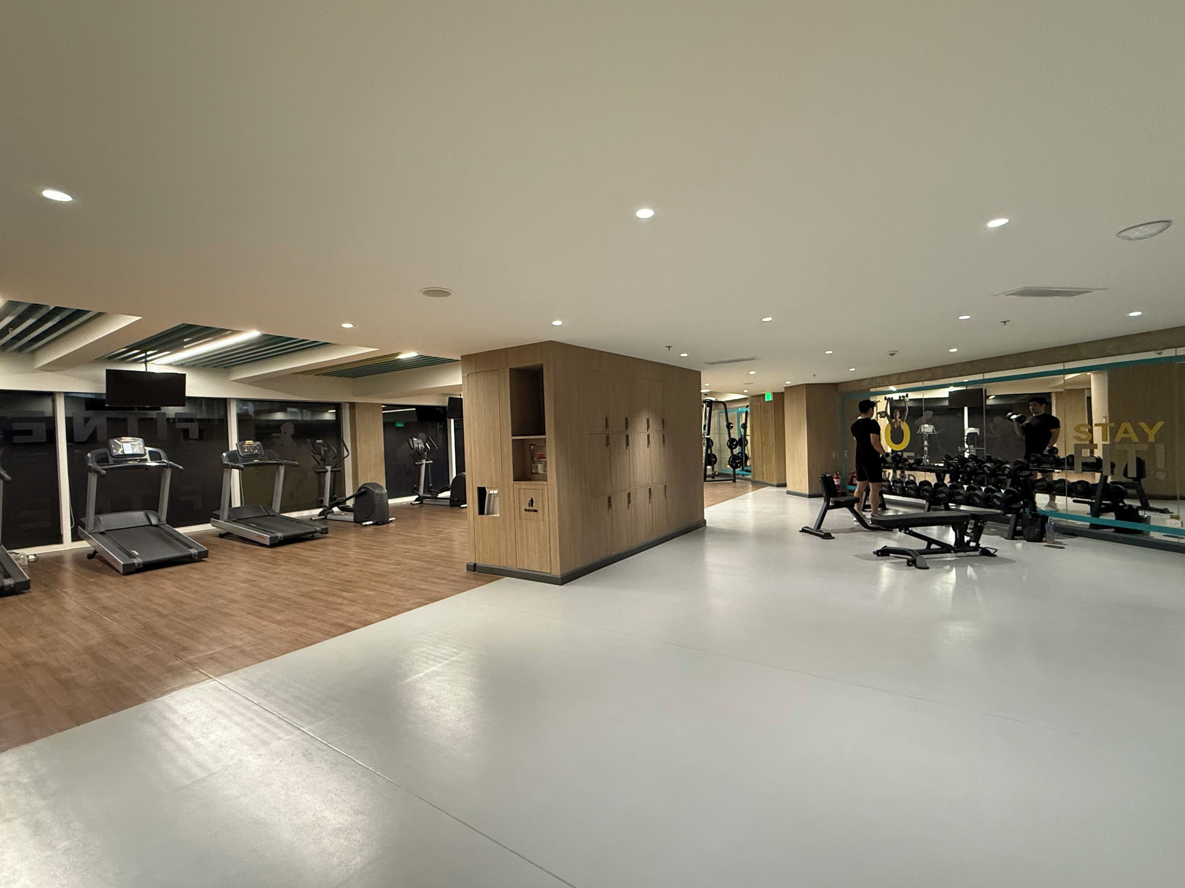 Une salle de sport moderne équipée de tapis de course, d’appareils de musculation et d’un mur recouvert de miroirs.