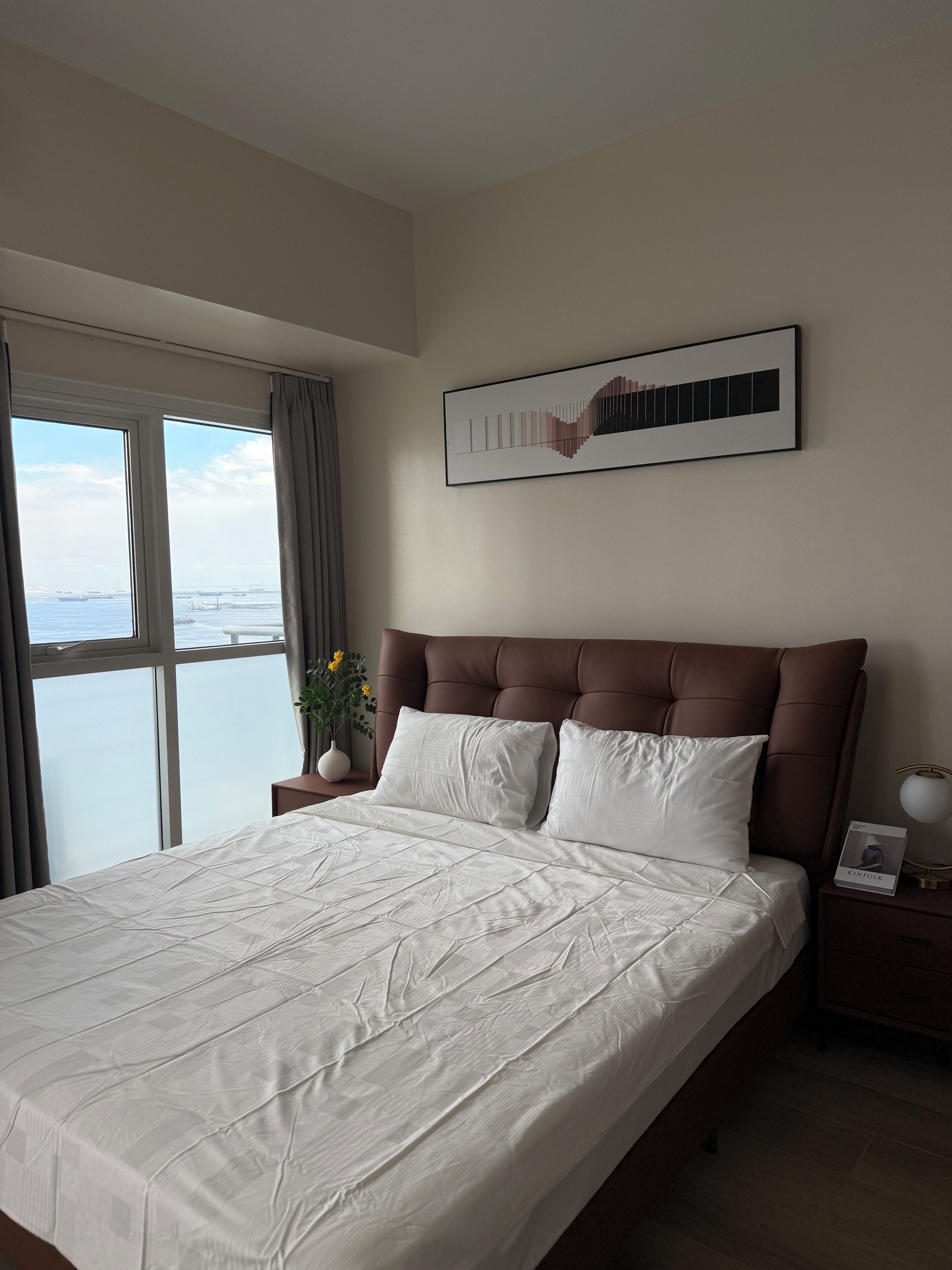 Une chambre d’hôtel avec un grand lit, une vue sur la mer et une œuvre d’art encadrée au mur.