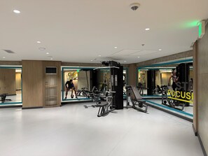 Un gimnasio con equipamiento de ejercicio, espejos y un diseño moderno y limpio.
