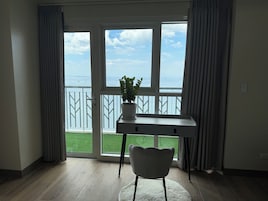 Una habitación con vista al mar, un escritorio, una silla y una planta en maceta.