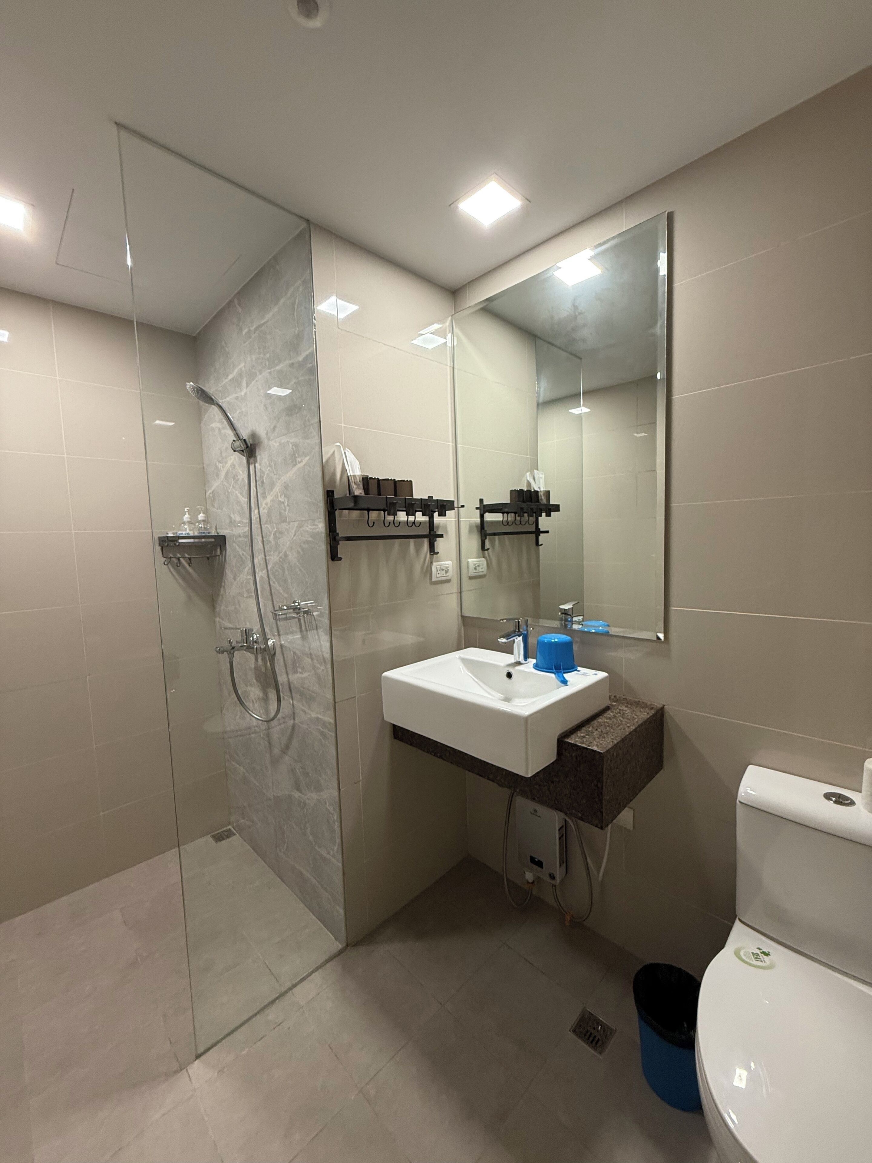 A modern bathroom with a glass shower enclosure, a white sink with a marble countertop, and a large mirror.
