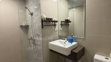 A modern bathroom with a glass shower enclosure, a white sink with a marble countertop, and a large mirror.