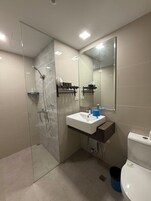 A modern bathroom with a glass shower enclosure, a white sink with a marble countertop, and a large mirror.