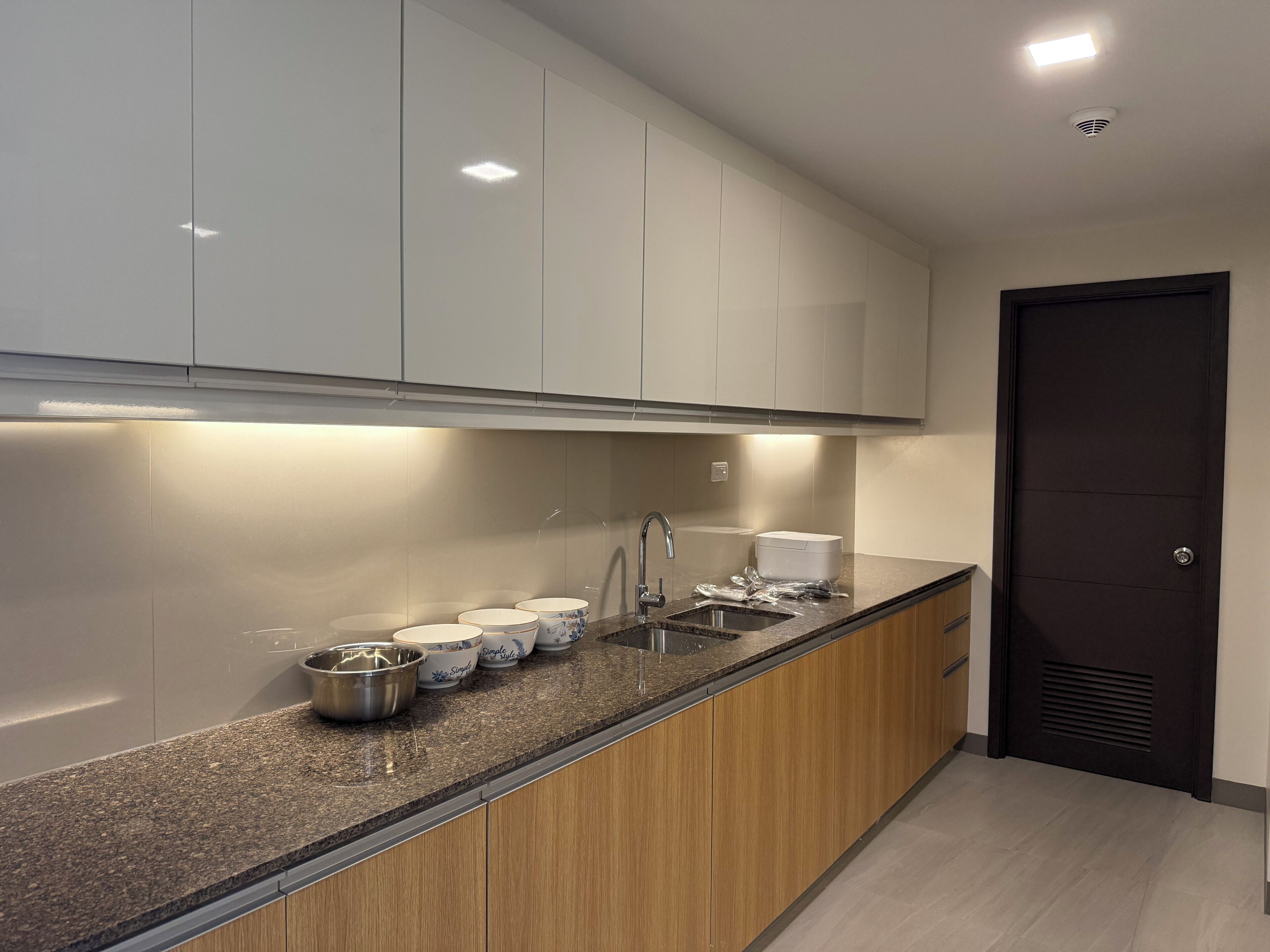 Une cuisine moderne avec des meubles blancs, un plan de travail en granit et un évier en acier inoxydable.