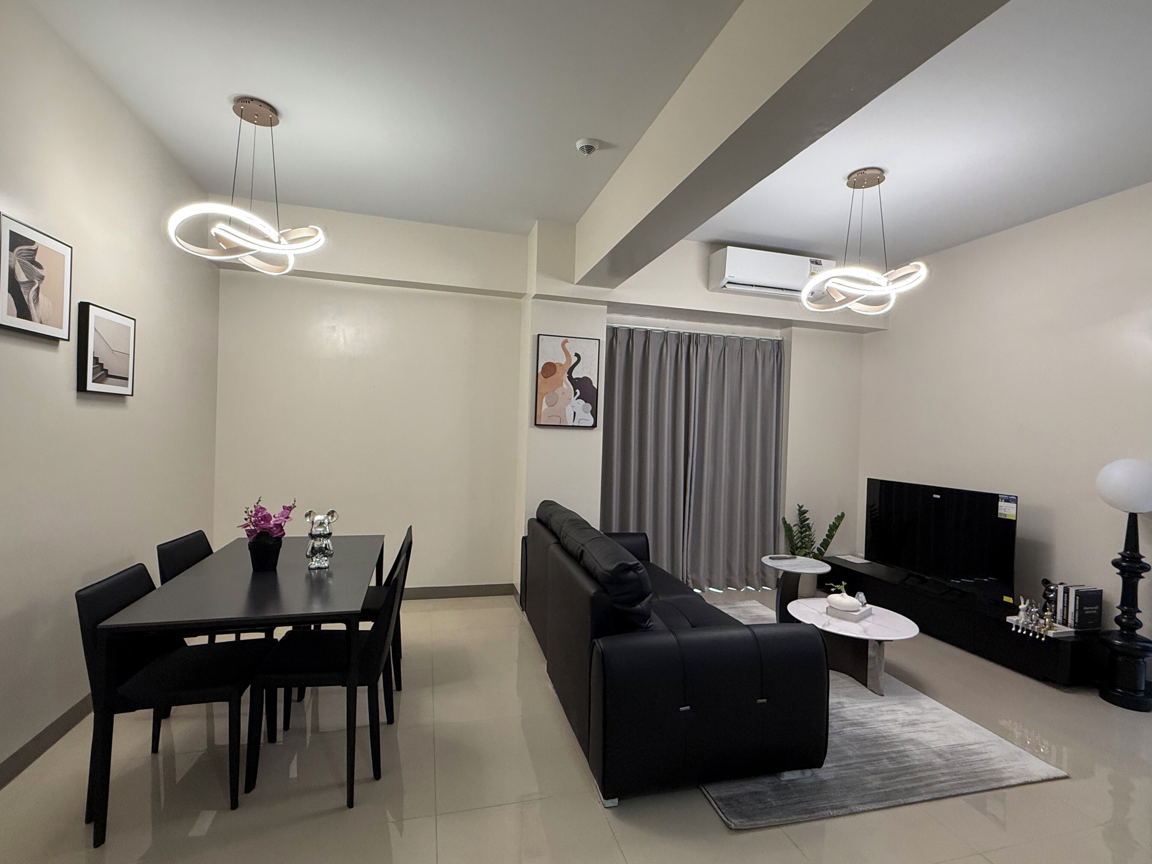 A modern living room with a dining area, a sofa, a TV, and a fireplace.
